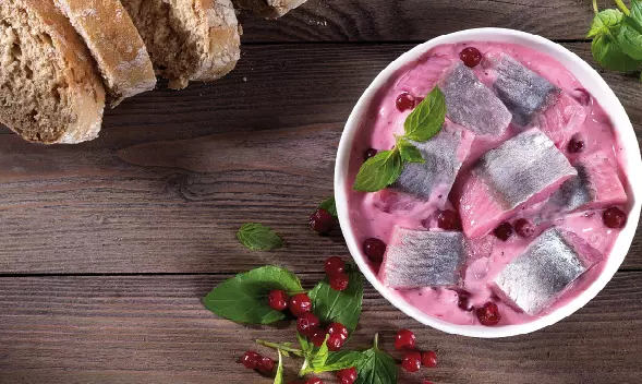 Hering in pinker Sahnesoße mit Beeren in Schüssel