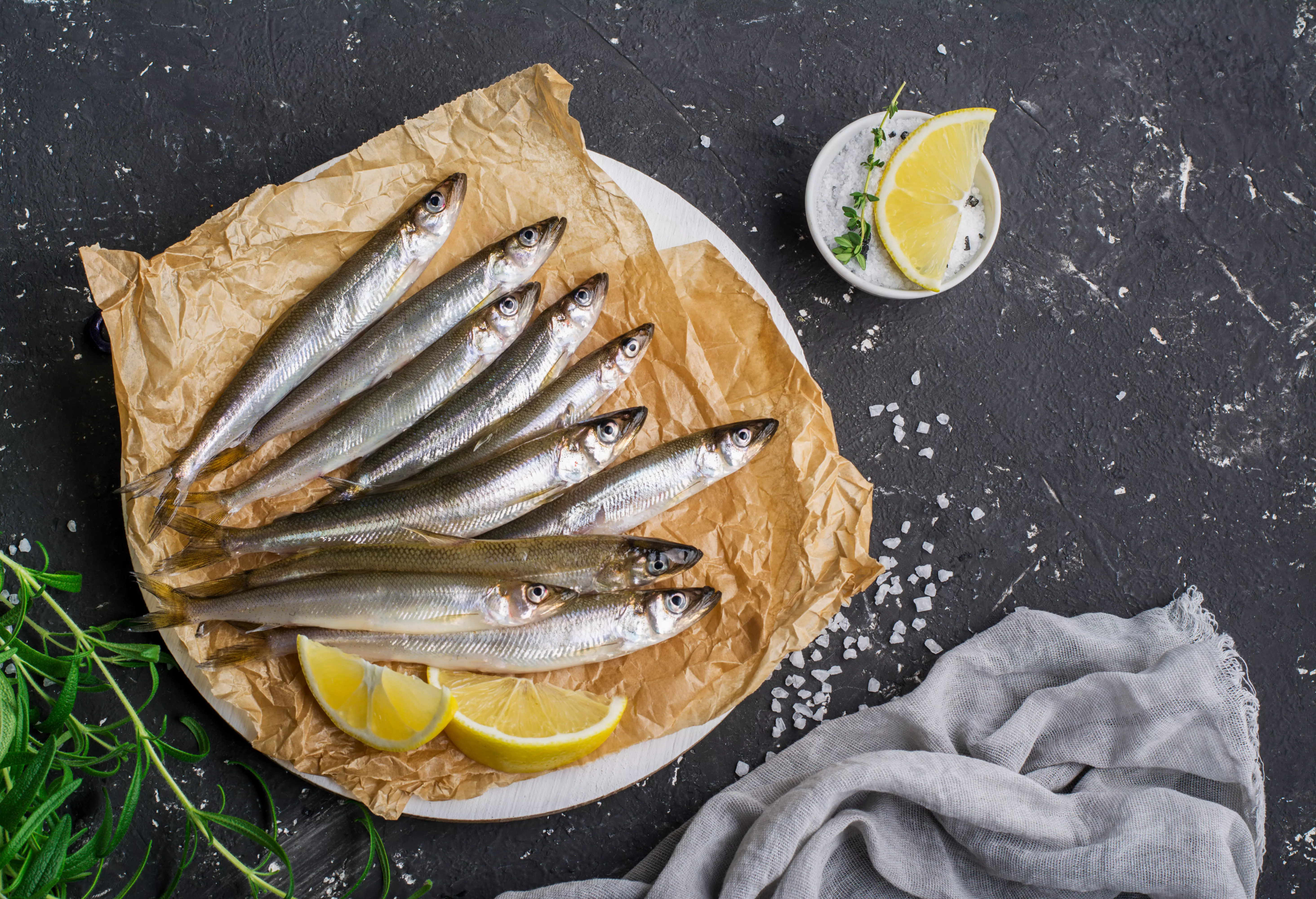 Rohe Sprotten auf Papier mit Zitronenscheiben