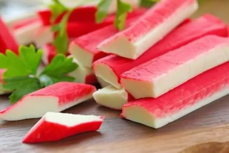 rote Surimi-Sticks auf Holzbrett mit Petersilie