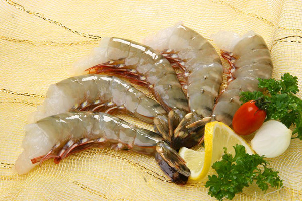 rohe Garnelen, angerichtet mit Zitrone und Gemüse