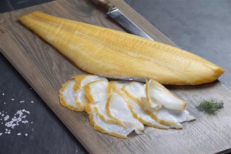 aufgeschnittenes geräuchertes Schellfischfilet auf Holzbrett