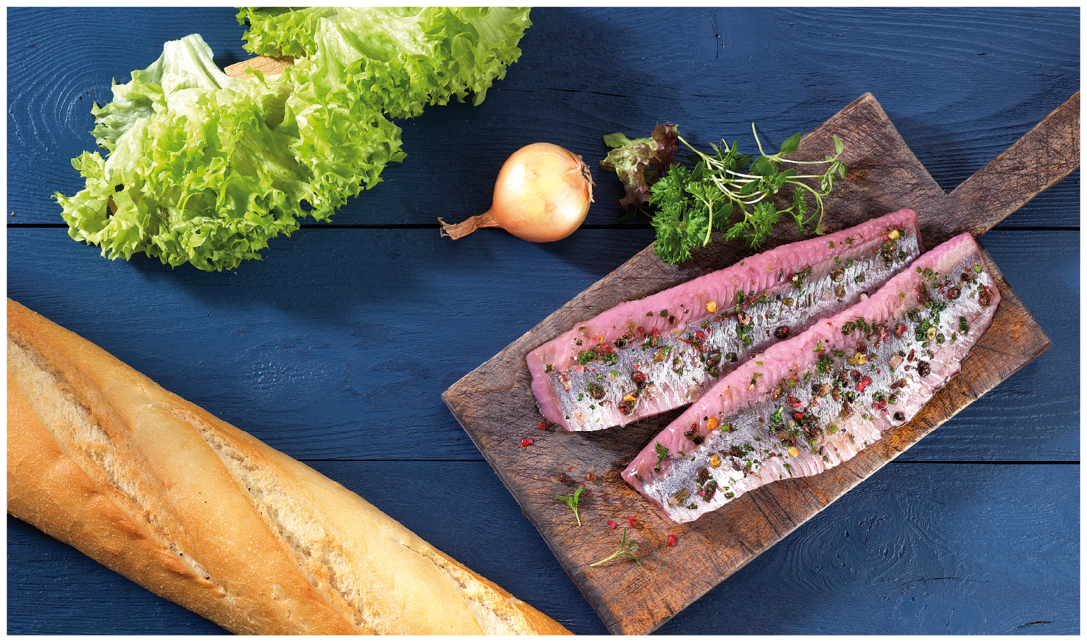 zwei gewürzte Matjesfilets mit Kräutern auf Holzbrett