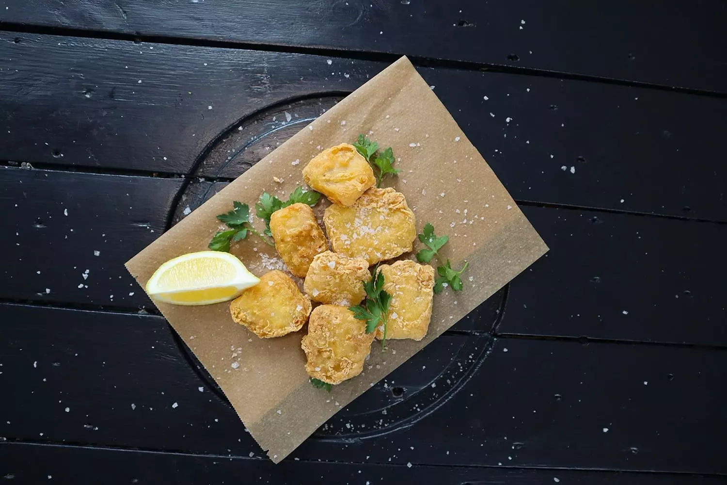 knusprig panierte Backfischwürfel mit Zitrone auf Papier