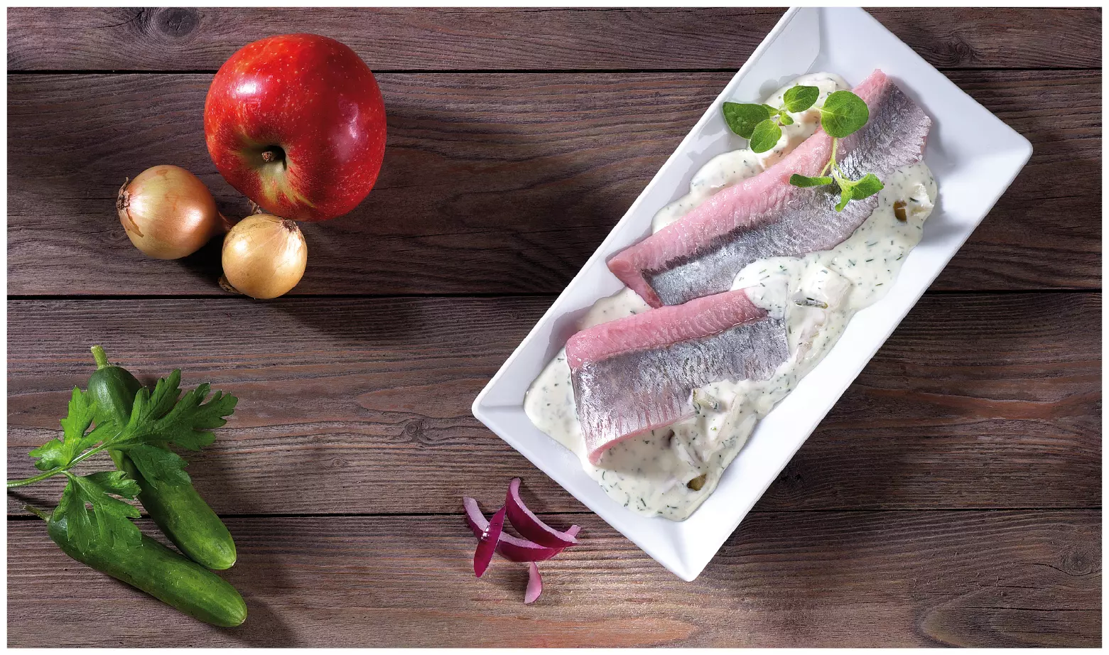 Matjesfilets in Sahnesauce auf rechteckigem Teller angericht