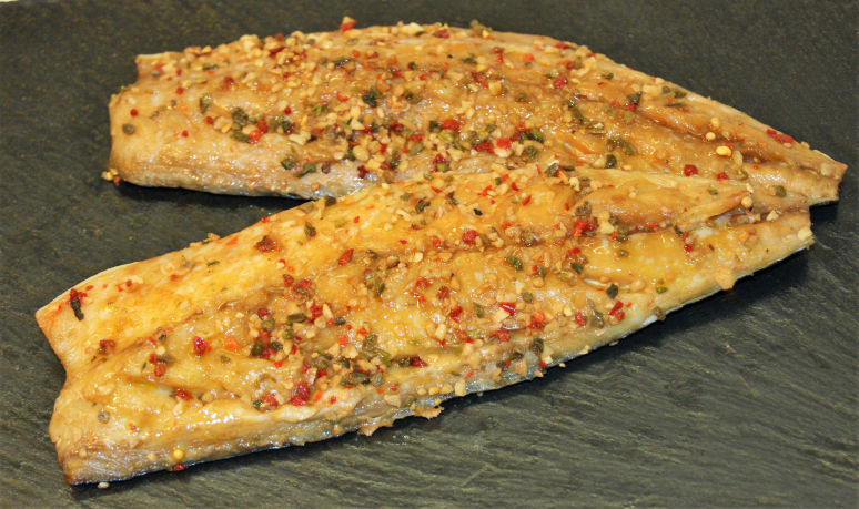zwei gewürzte Makrelenfilets auf dunkler Platte