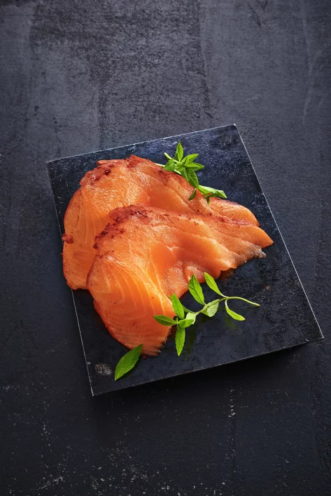 Räucherlachs in Scheiben mit Kräutern auf Schieferplatte